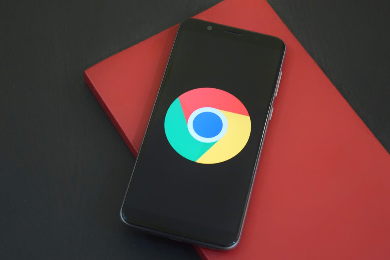 Services Close-up of a smartphone with Chrome browser logo on screen placed on a red notebook.